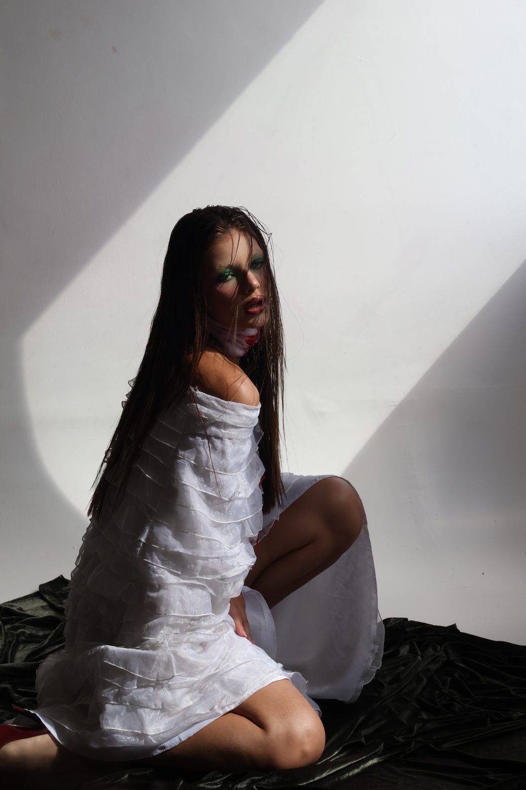 Animal, ela sentada no chão, vestido claro, o olhar em guarda
