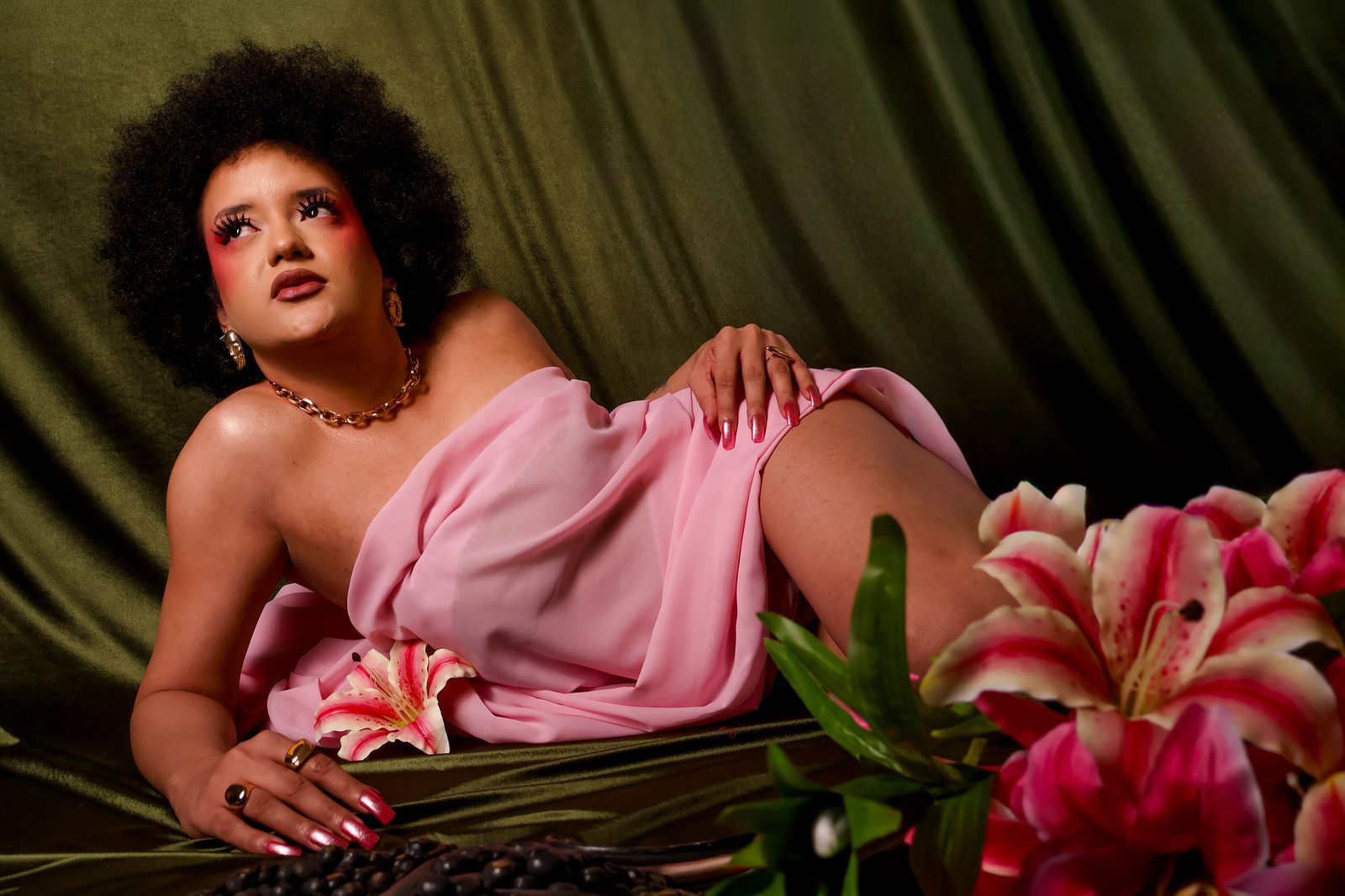 Blossom, Joana deitada em pose, corpo inteiro, entre os tecidos verde e rosa